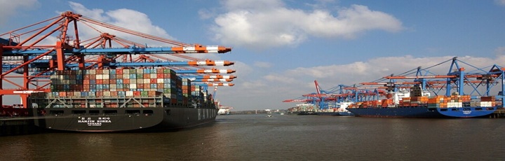 Operación de contenedores en terminal europeo con skyline urbano al fondo