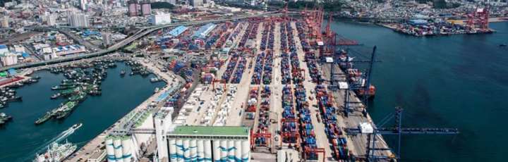 Vista portuaria con grúas STS y buque portacontenedores al atardecer, alusiva al corredor verde transpacífico